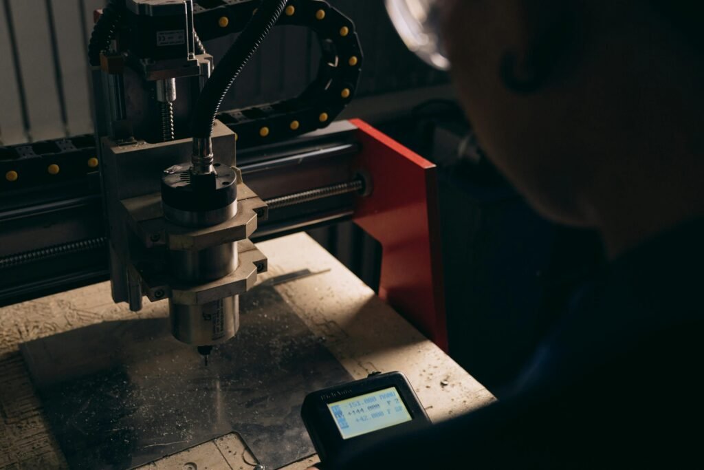 A detailed view of a CNC machine being operated by a person indoors with dim lighting.